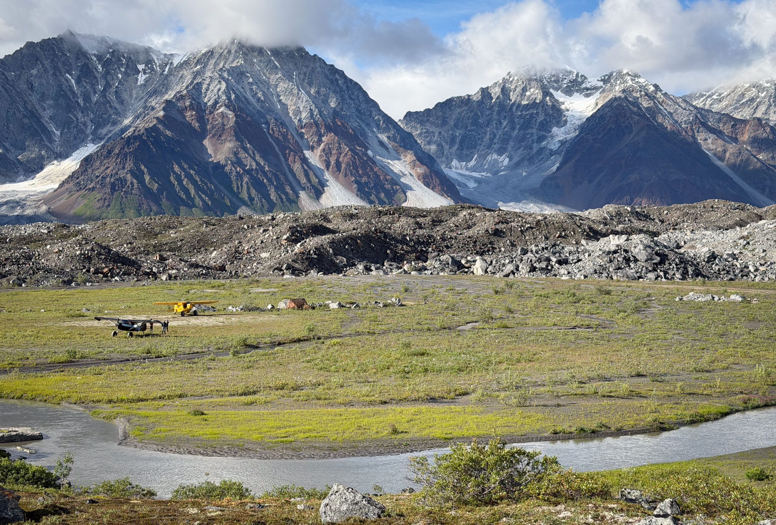 Two airplanes gathered on a remote bush airstrip in the Alaska Range